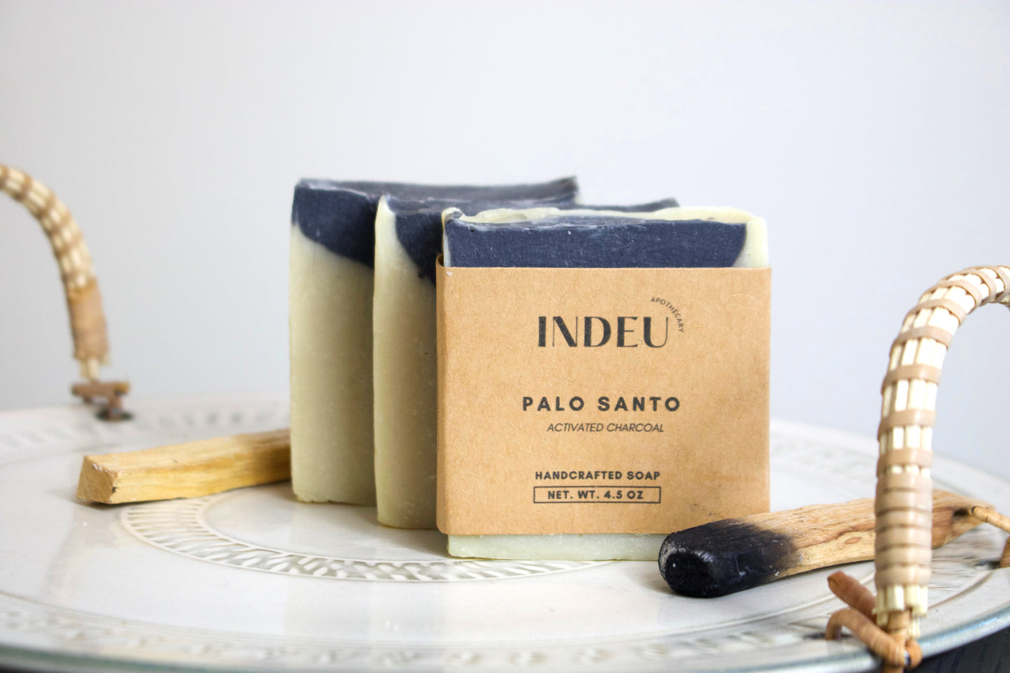 Three bars of Palo Santo soap with a cardboard packaging labeled 'INDEU' on a white surface.